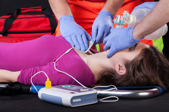 Paramedics using defibrillator on a patient