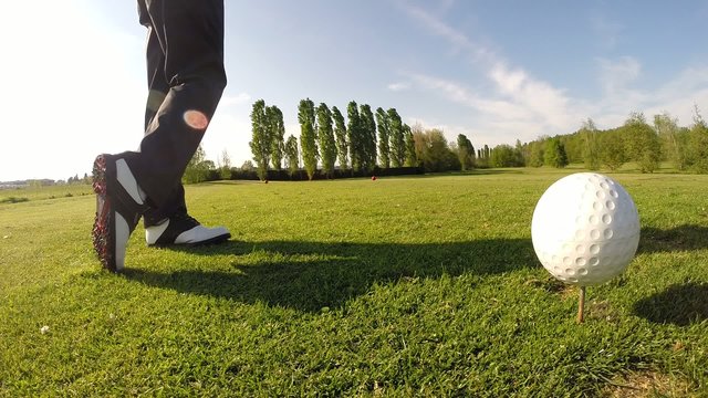 Golfer performs a golf shot from the tee. Sunny summer day.