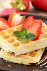 Stack of freshly baked Belgian waffles with strawberries