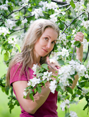 Fototapeta premium young attractive woman standing near blossoming apple tree...