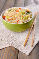 Tasty instant noodles with vegetables in bowl on table close-up