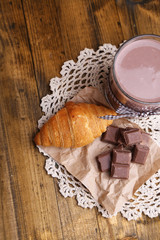 Chocolate milk in glass, on wooden table background