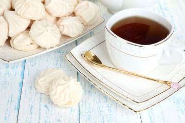 Cup of tea with meringues on table close-up