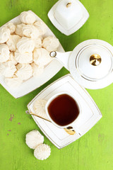 Cup of tea with meringues on table close-up
