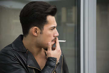 Fototapeta na wymiar Handsome young man with leather jacket smoking