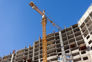 Tall buildings under construction with crane against a blue sky