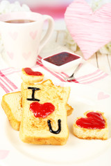Delicious toast with jam and cup of tea on table close-up