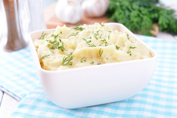 Delicious mashed potatoes with greens in bowl on table close-up