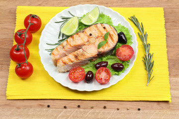Tasty grilled salmon with vegetables, on wooden table