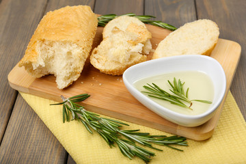 Fresh bread with olive oil and rosemary on wooden table