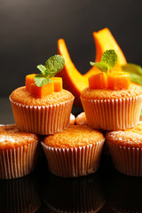 Tasty pumpkin muffins on dark background