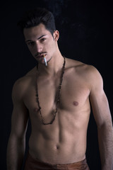 Fototapeta na wymiar Athletic shirtless young man with mustache smoking