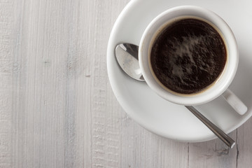 Cup of coffee from above on white wooden table