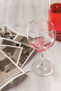 Memories. Bottle of rose wine, wine glass and old photos