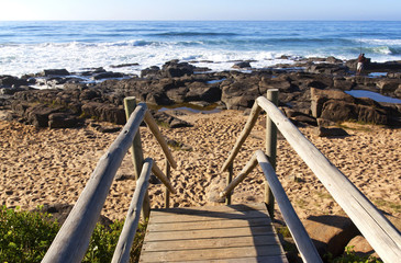 Weathered Wooden Stairway Leading onto Rocky Beach