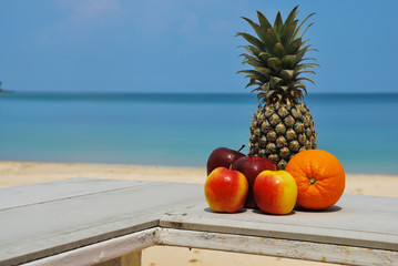Orange pineapple apple on the beach