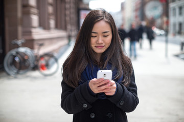 Young Asian woman texting message walking street
