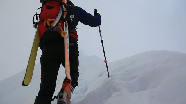 Ski mountaineer walking up along a steep snowy ridge