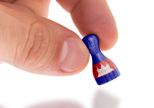 Hand holding wooden pawn, flag painting, selective focus