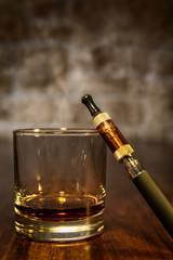 Stillleben mit E-Zigarette und Glas Bourbon