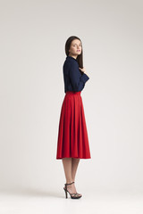 Fototapeta premium Young lady in dress posing on grey background. red