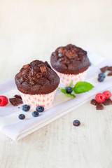 Two delicious homemade chocolate muffins in colored cooking pape