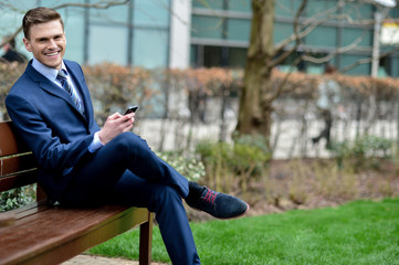 Businessman with his phone on the bench