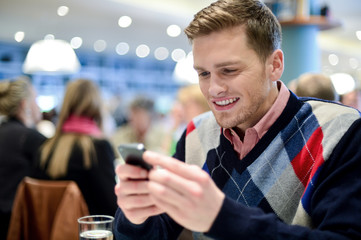 Young man in cafe and using his mobile phone