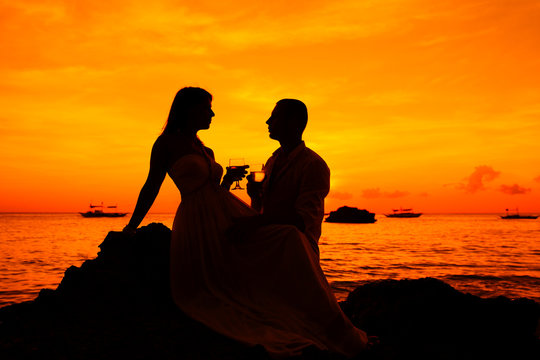 Romantic couple at tropical beach with sunset in the background