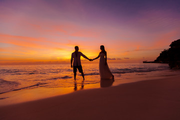 bride and groom on a tropical beach with the sunset in the backg © frolova_elena