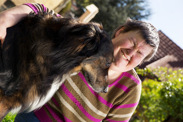behinderte Frau umarmt einen Hund im Freien