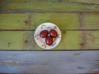 Три пасхальных яйца на тарелке, деревянный  стол