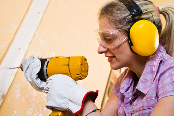 Female carpenter  at work using hand drilling machine