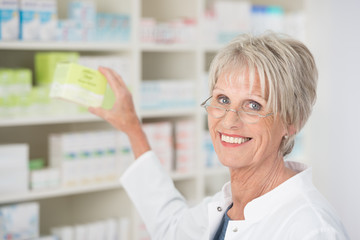 apothekerin nimmt verpackung aus dem regal
