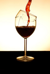 Pouring red vine into a broken glass