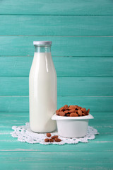 Almond milk in bottle with almonds in bowl,