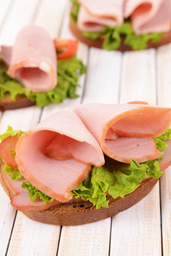 Delicious sandwiches with lettuce and ham on table close-up