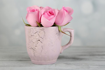 Beautiful roses in cup on light background