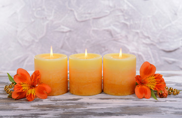 Beautiful candles with flowers on table on grey background