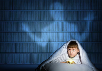 boy under the covers with a flashlight