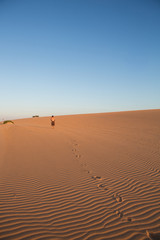 Fototapeta na wymiar Man walking in sand dunes in La Guajira, Colombia