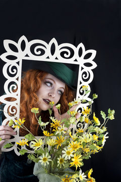 Woman with red hair wearing a top hat posing with picture frame