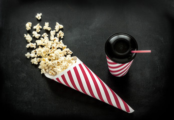 Cinema snacks - cornet popcorn and drink on black