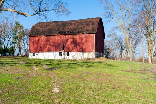 A weathered red barn on a hill