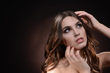 Fototapeta premium Beautiful young woman with long hair on dark brown background