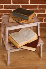 Books on wooden ladder on  color wall background
