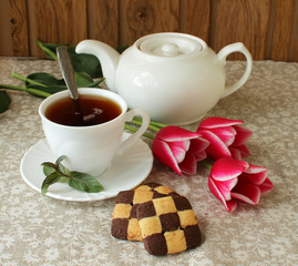 Cup of black tea, biscuits and tulips.