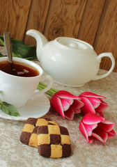 Cup of black tea, biscuits and tulips.
