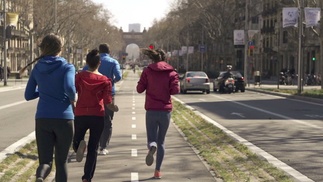 Young joggers running by the city street
