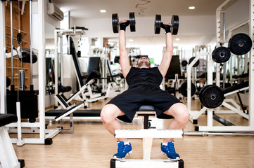 Fototapeta na wymiar young man training at gym with dumbbell, chest bench exercise